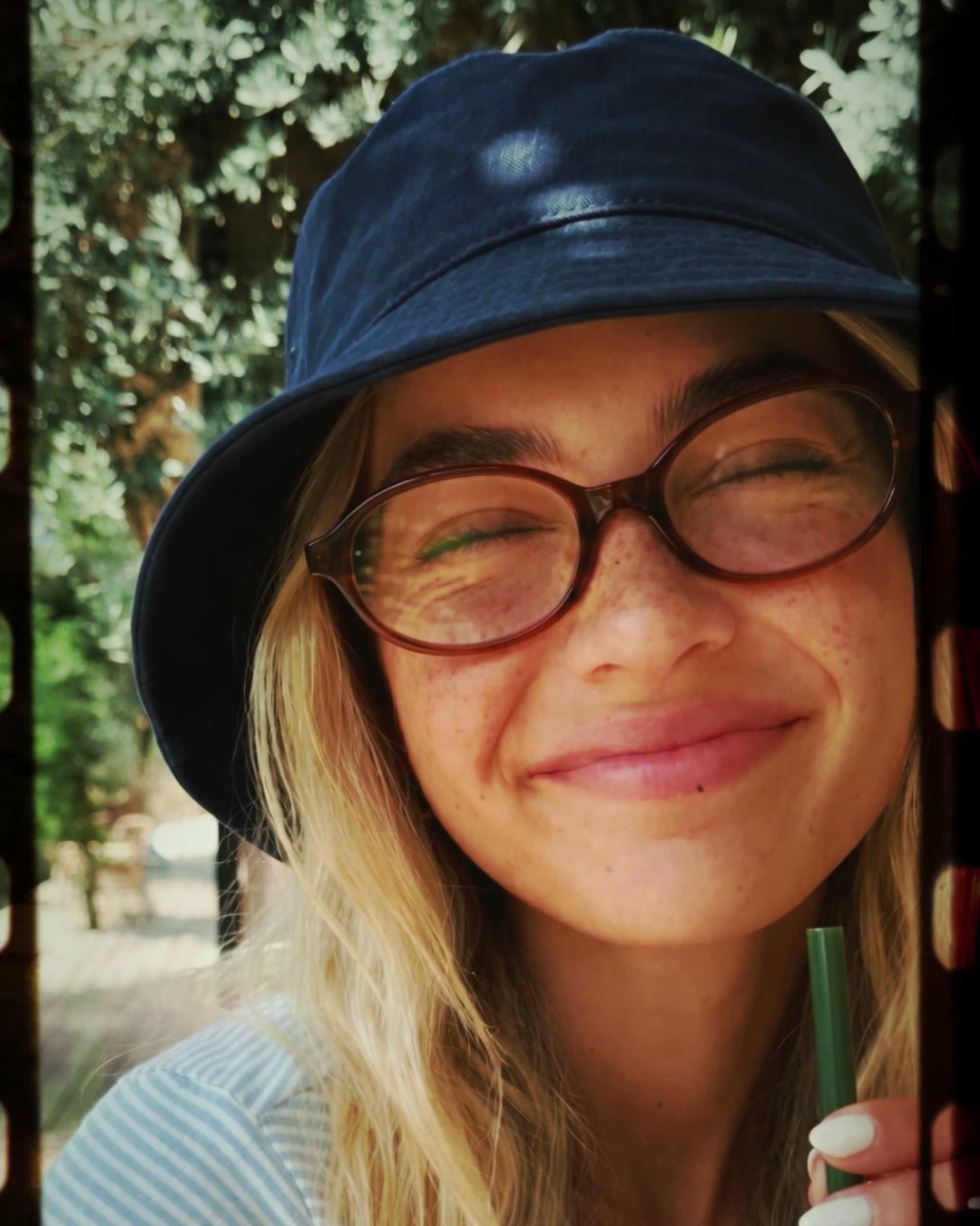 Smiling woman in a bucket hat with an iced coffee straw